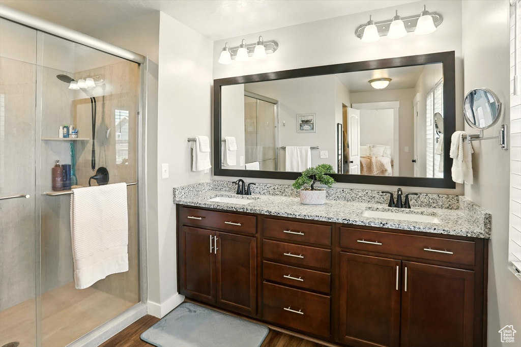 Bathroom featuring connected bathroom, wood finished floors, a stall shower, and double vanity