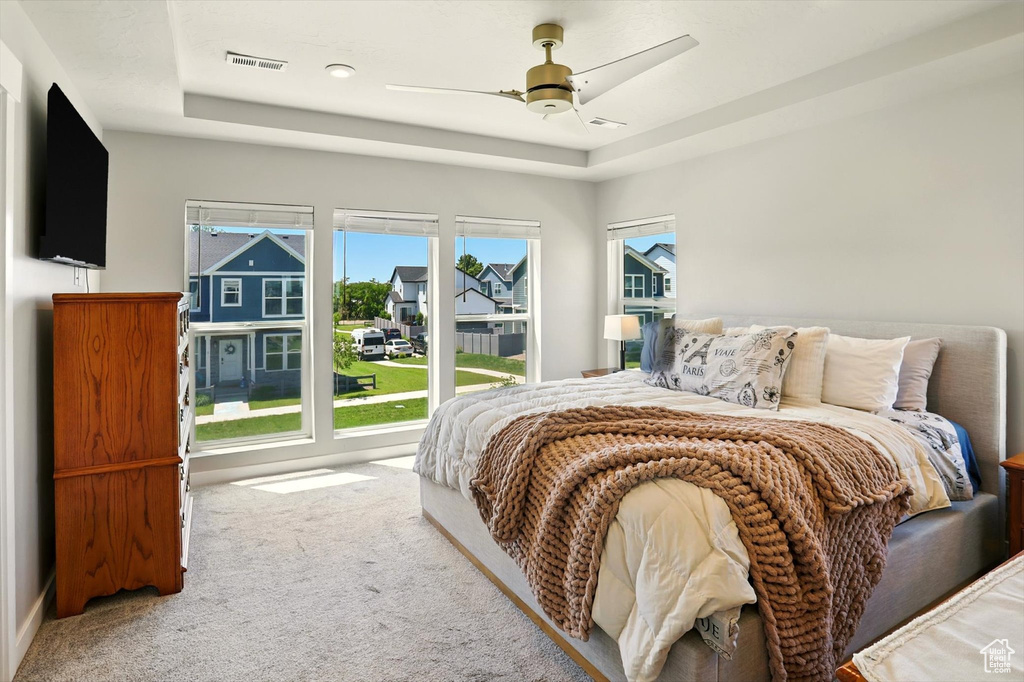 Bedroom featuring a raised ceiling, carpet floors, ceiling fan, and a residential view