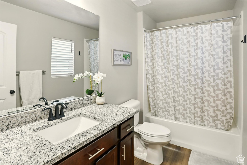 Full bathroom with vanity, wood finished floors, and shower / tub combo with curtain