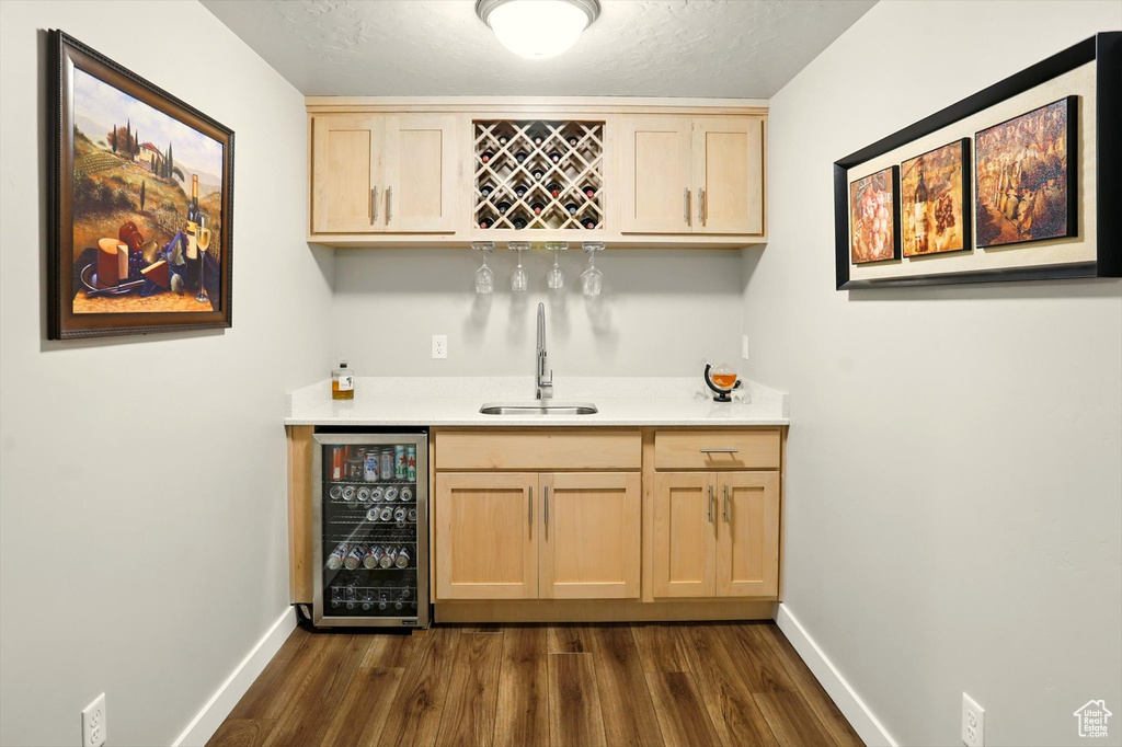 Indoor wet bar featuring wine cooler, dark wood finished floors, and a textured ceiling