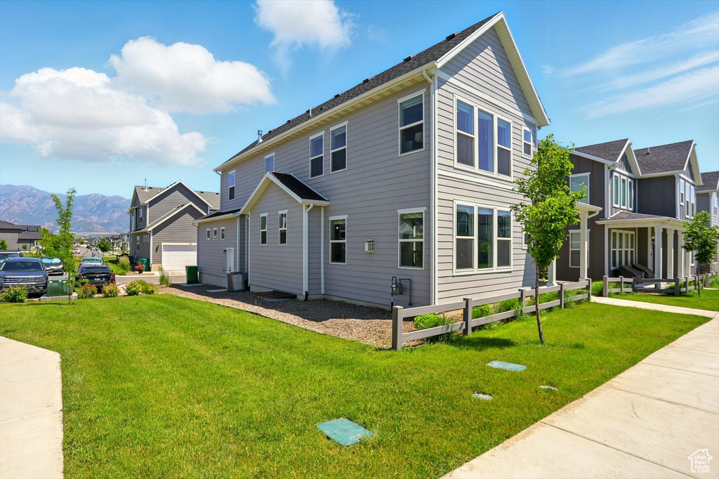 View of side of home featuring a mountain view, a lawn, and a residential view