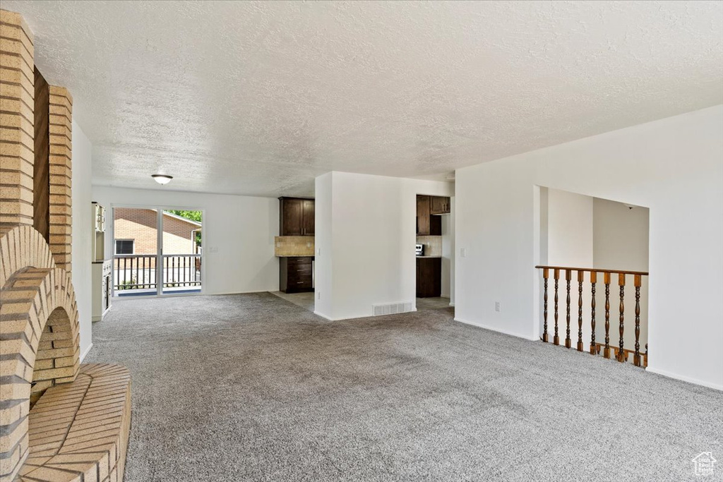 Unfurnished living room featuring a textured ceiling and carpet flooring