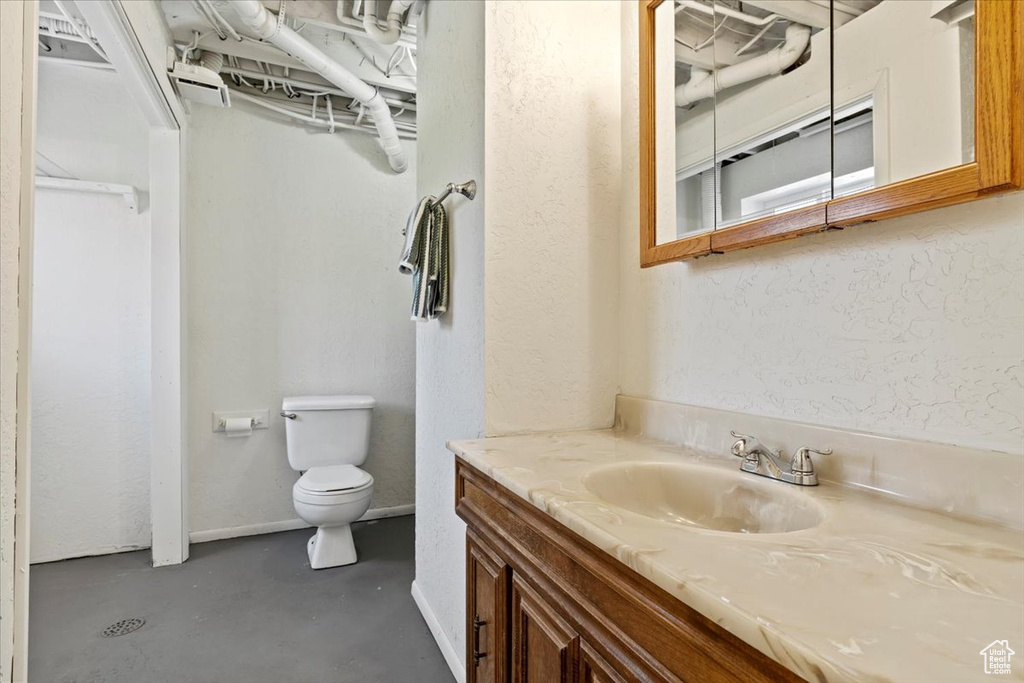 Bathroom with vanity, concrete floors, and a textured wall