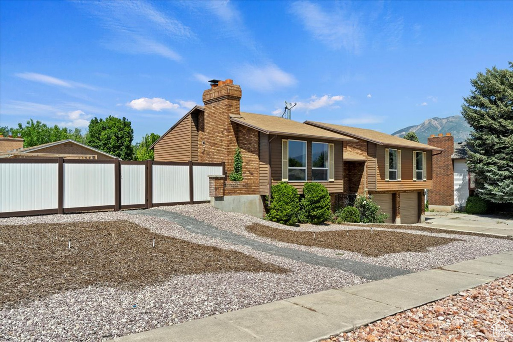 View of front of home with a chimney, driveway, an attached garage, and a mountain view