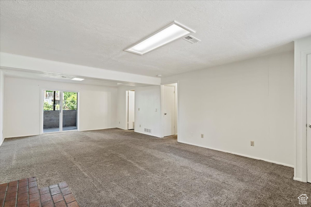 Carpeted empty room with a textured ceiling and baseboards