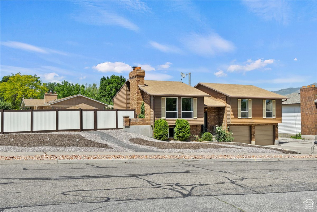 View of front of home with concrete driveway, an attached garage, and a chimney