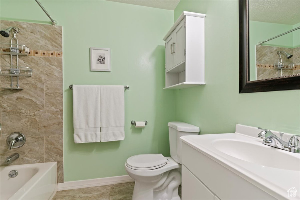 Bathroom featuring vanity, washtub / shower combination, a textured ceiling, and tile patterned floors