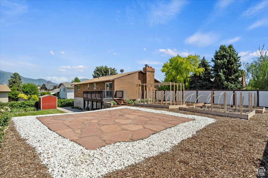 View of yard with a shed, a patio area, and a deck with mountain view
