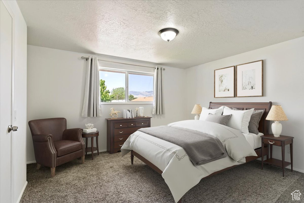 Carpeted bedroom featuring a textured ceiling and baseboards