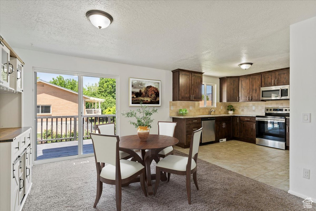Dining area featuring light colored carpet, a textured ceiling, and light tile patterned floors