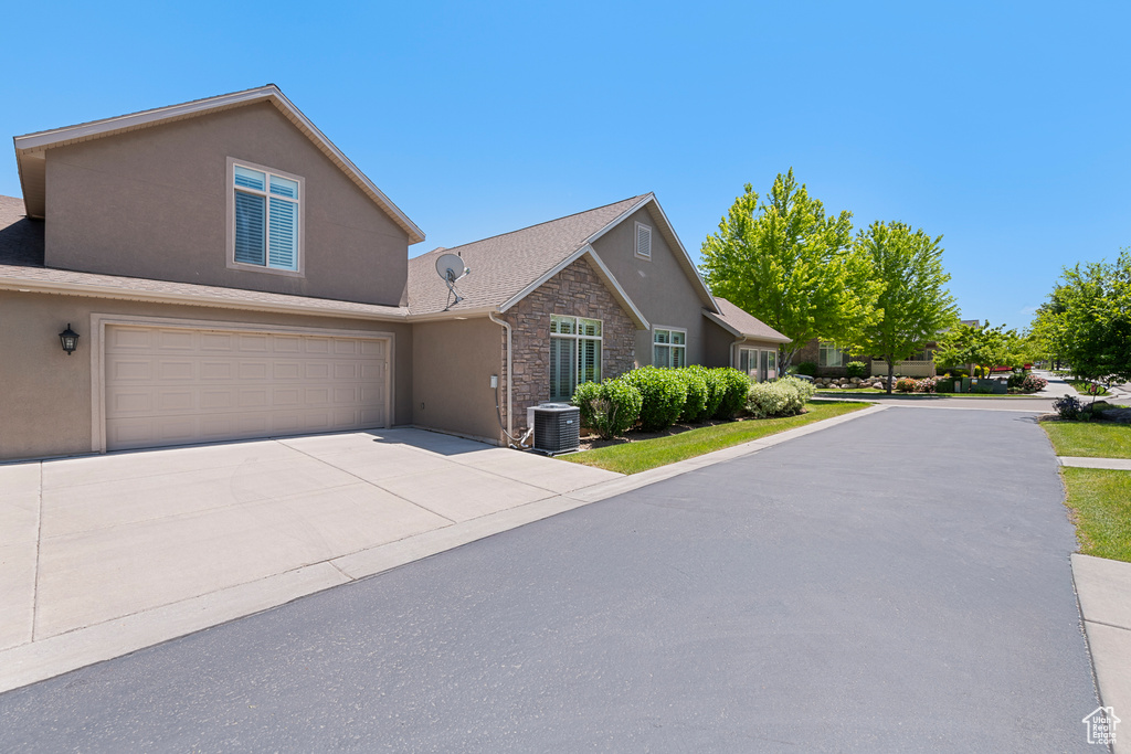 View of front facade featuring stone siding, stucco siding, concrete driveway, and a garage