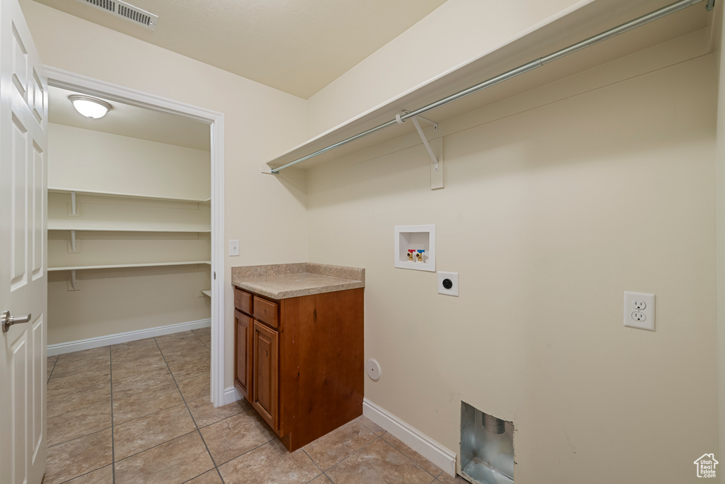 Laundry room with hookup for an electric dryer, washer hookup, and light tile patterned floors
