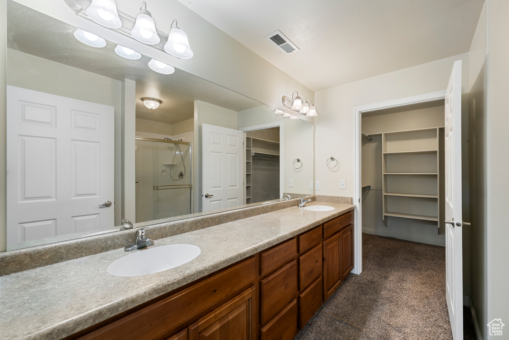 Bathroom featuring a shower stall, a walk in closet, and double vanity