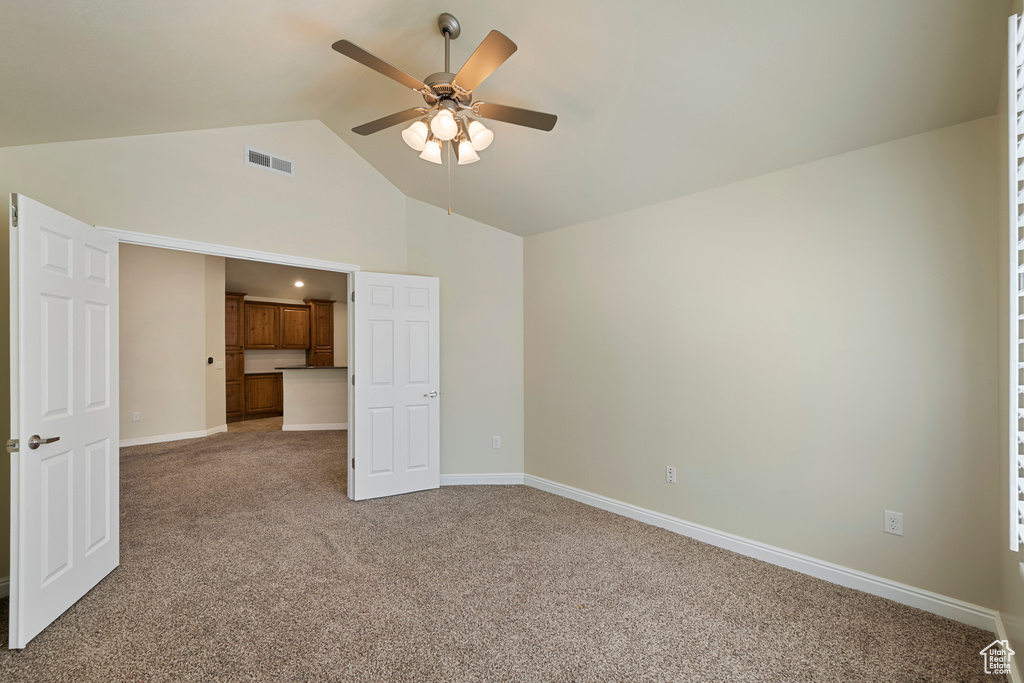 Unfurnished bedroom featuring light carpet, high vaulted ceiling, and ceiling fan
