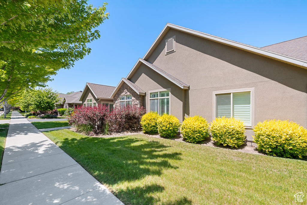 View of side of home featuring stucco siding, stone siding, and a yard