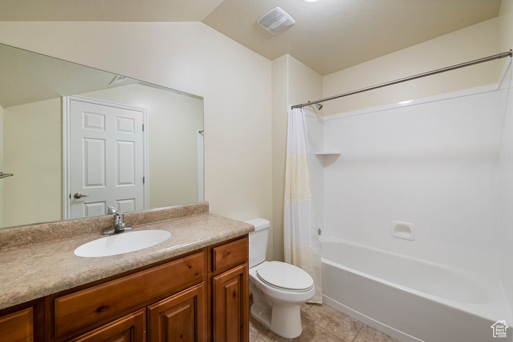 Bathroom featuring vanity, shower / bath combo with shower curtain, tile patterned flooring, and lofted ceiling