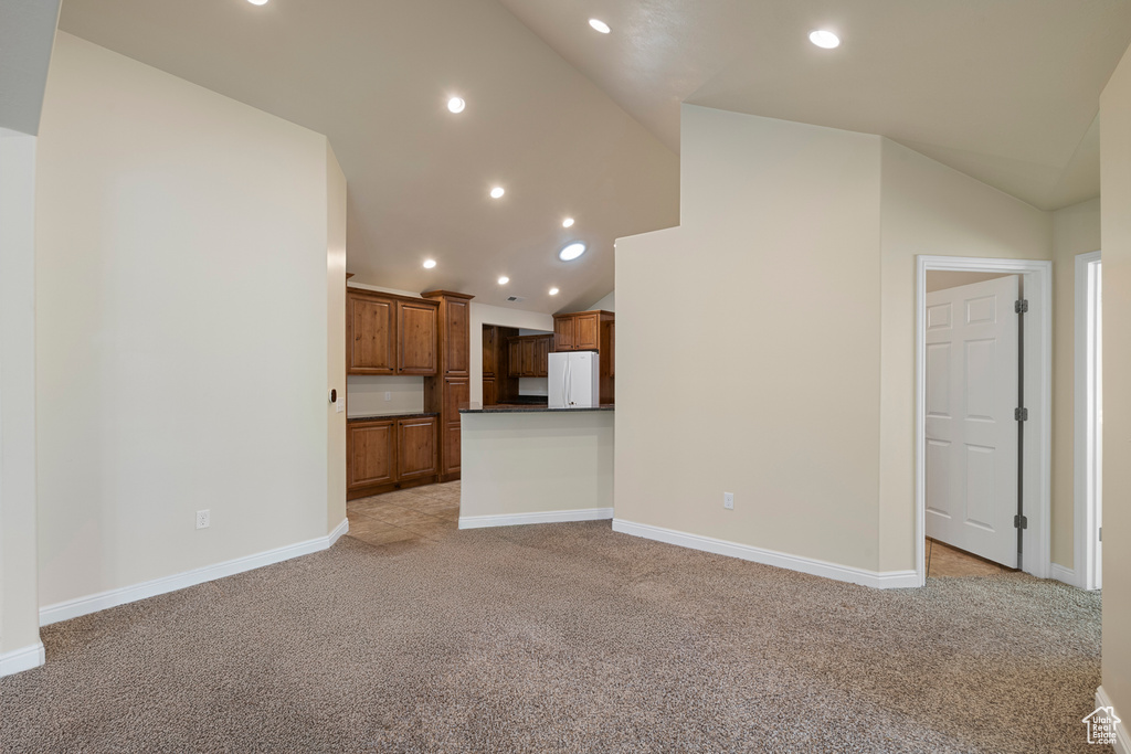 Unfurnished living room featuring light carpet, recessed lighting, and high vaulted ceiling
