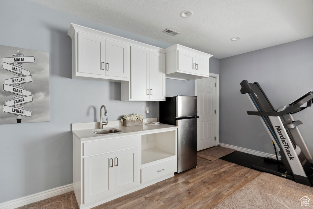 Kitchen with freestanding refrigerator, white cabinetry, light wood-style floors, light countertops, and recessed lighting