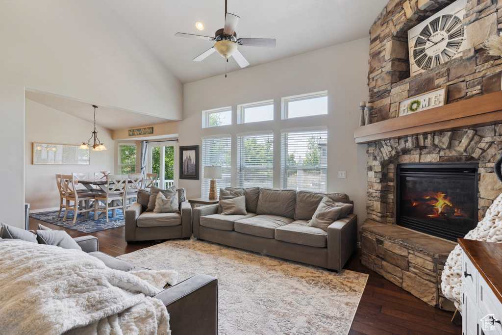 Living area with high vaulted ceiling, hardwood / wood-style floors, a fireplace, and a ceiling fan