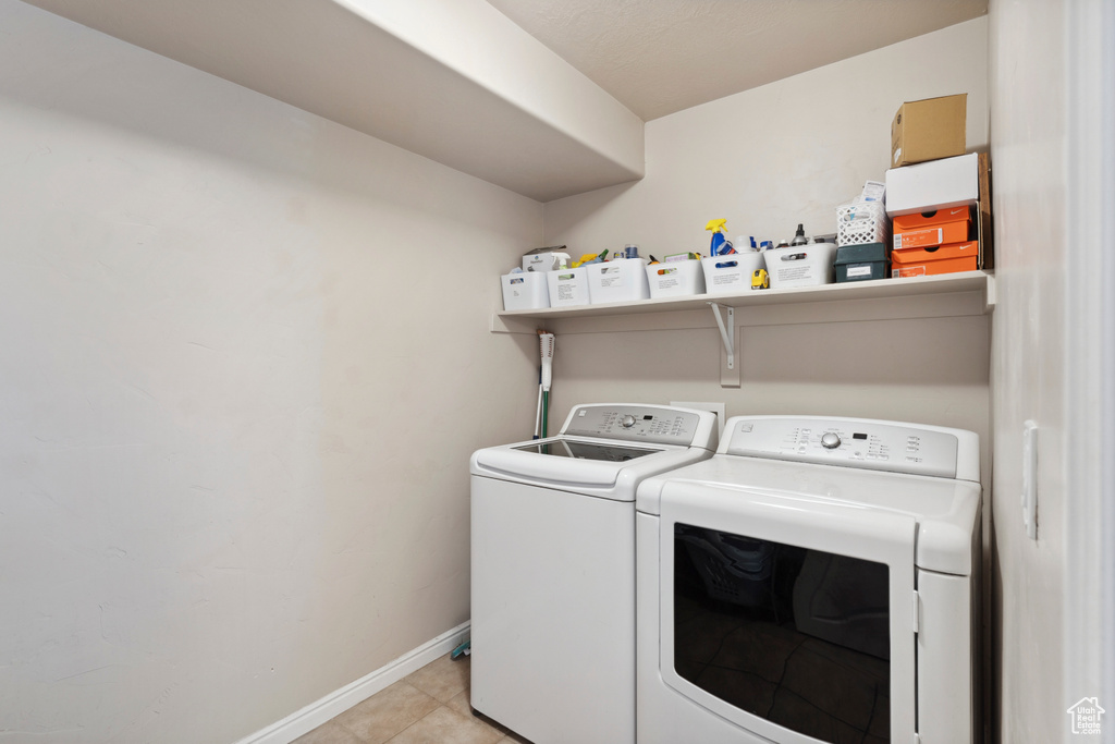 Laundry area with washing machine and clothes dryer and light tile patterned floors