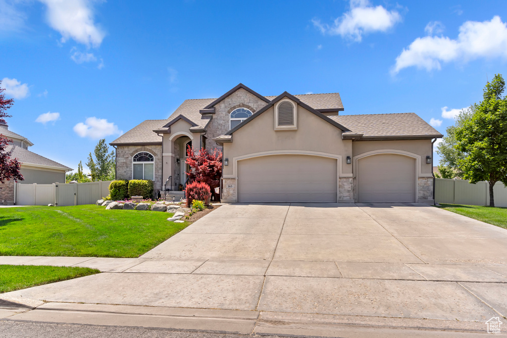 View of front of house with a garage, stucco siding, concrete driveway, stone siding, and a shingled roof