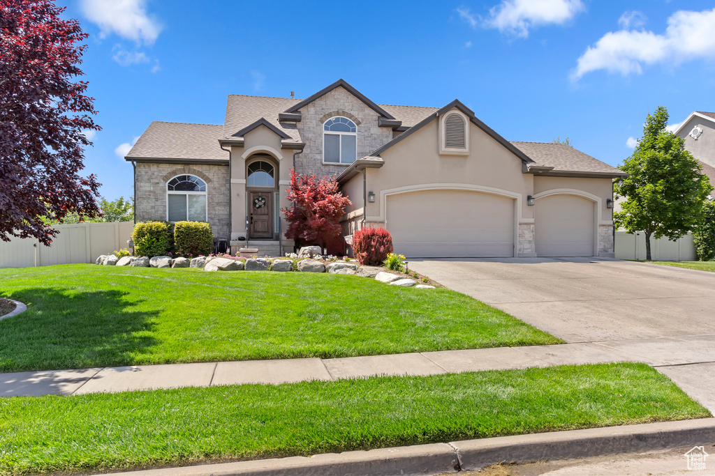 View of front facade with stone siding, stucco siding, a garage, driveway, and a shingled roof
