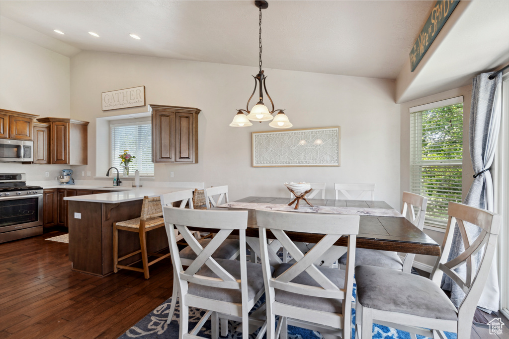 Dining room with plenty of natural light, dark wood finished floors, high vaulted ceiling, and a chandelier