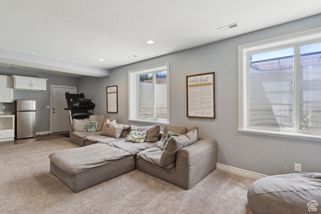 Living area featuring light carpet, plenty of natural light, and recessed lighting