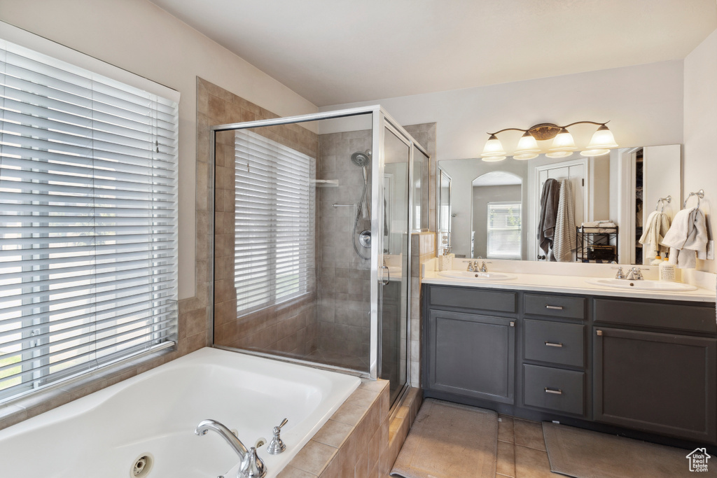 Bathroom with a tub with jets, a shower stall, double vanity, and tile patterned flooring