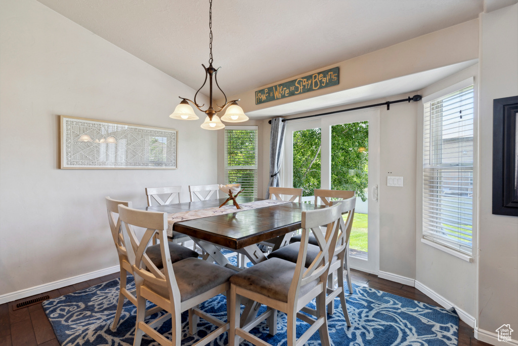 Dining space with a chandelier, dark wood-style flooring, and lofted ceiling