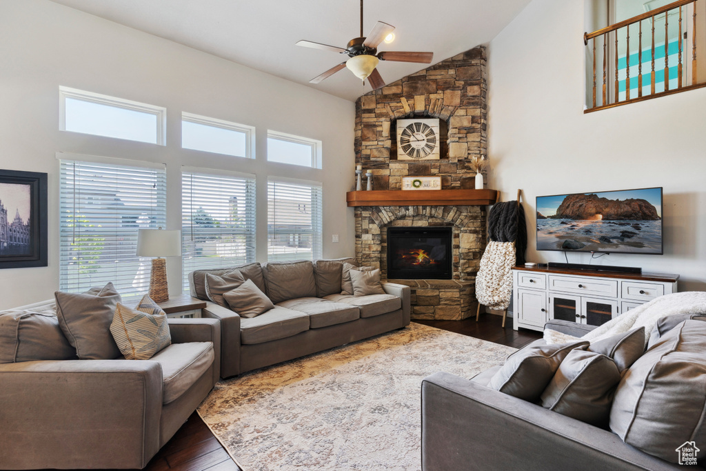 Living area with a ceiling fan, dark wood finished floors, high vaulted ceiling, and a fireplace