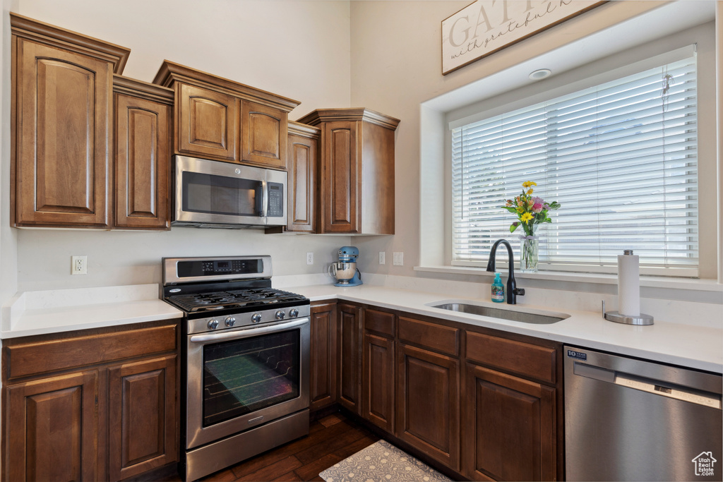 Kitchen with stainless steel appliances, light countertops, and dark wood-type flooring