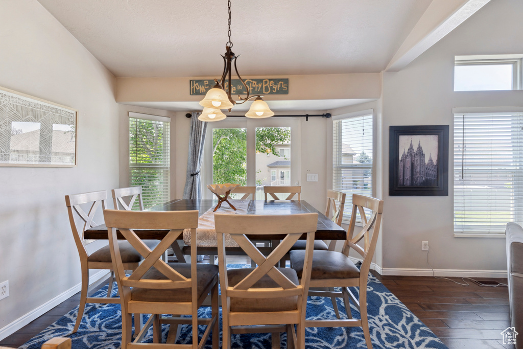 Dining space with healthy amount of natural light, dark wood finished floors, and a chandelier