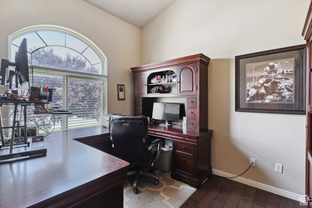Office space with dark wood-style floors and lofted ceiling