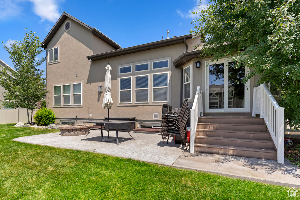 Rear view of house featuring stucco siding, an outdoor fire pit, and a patio area