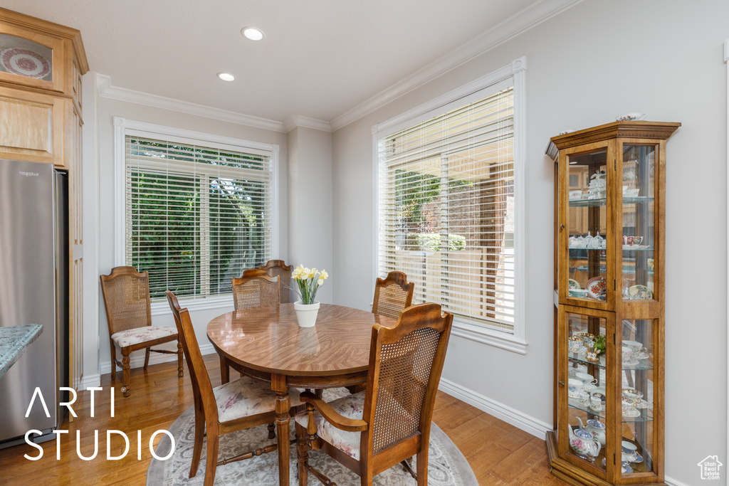 Dining area with ornamental molding, light wood finished floors, and recessed lighting