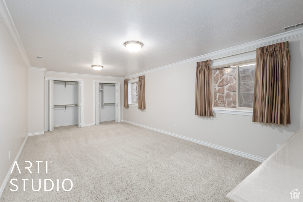Unfurnished bedroom with multiple closets, carpet floors, and ornamental molding