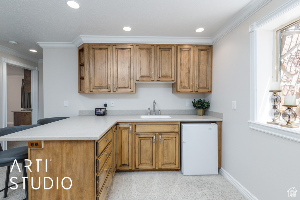 Kitchen featuring refrigerator, light countertops, recessed lighting, a peninsula, and crown molding