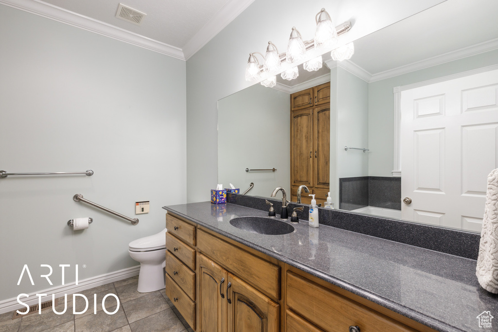 Bathroom with vanity, crown molding, and tile patterned flooring