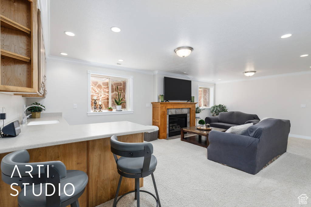 Kitchen featuring a peninsula, ornamental molding, a kitchen bar, recessed lighting, and carpet