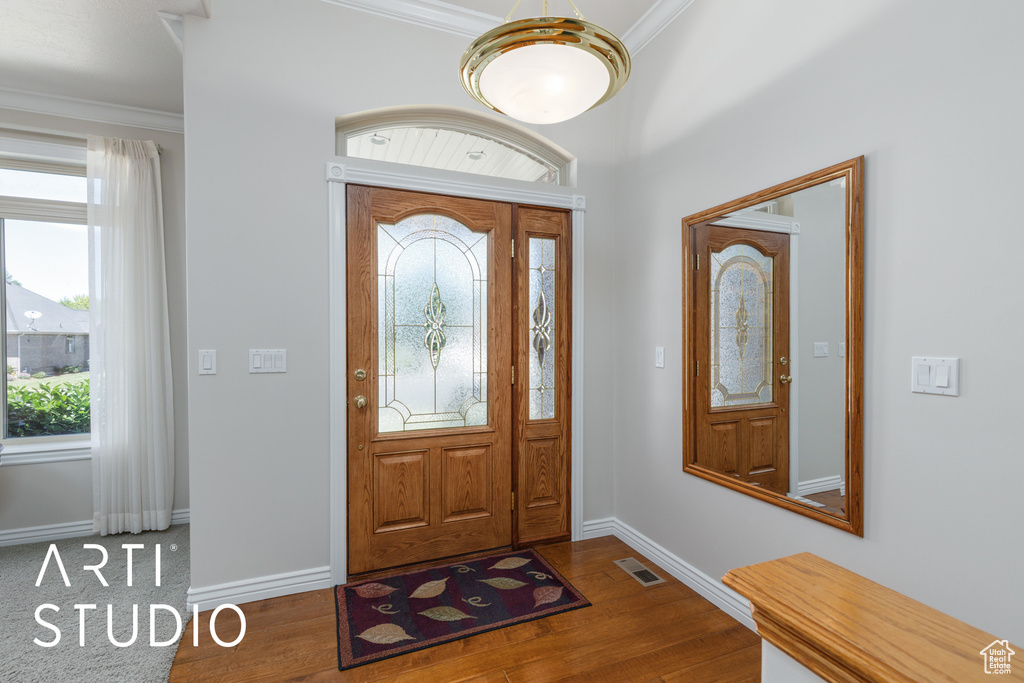 Entryway featuring healthy amount of natural light, wood finished floors, and ornamental molding