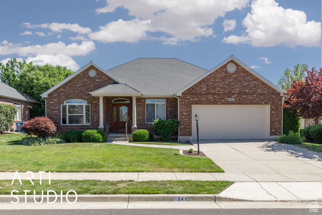 View of front of property featuring a garage, a front yard, driveway, brick siding, and roof with shingles