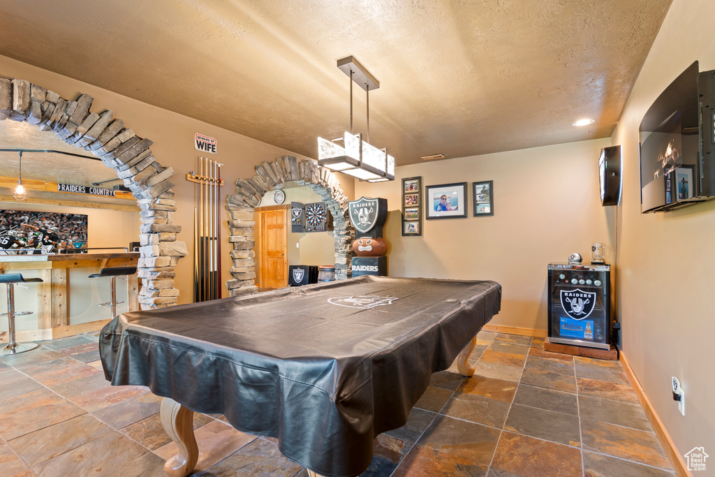 Playroom with stone tile floors, billiards table, a textured ceiling, a bar, and recessed lighting