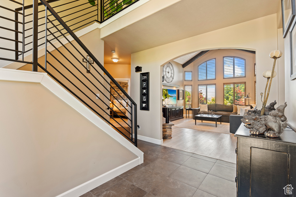 Foyer entrance with arched walkways, stairs, and tile patterned flooring
