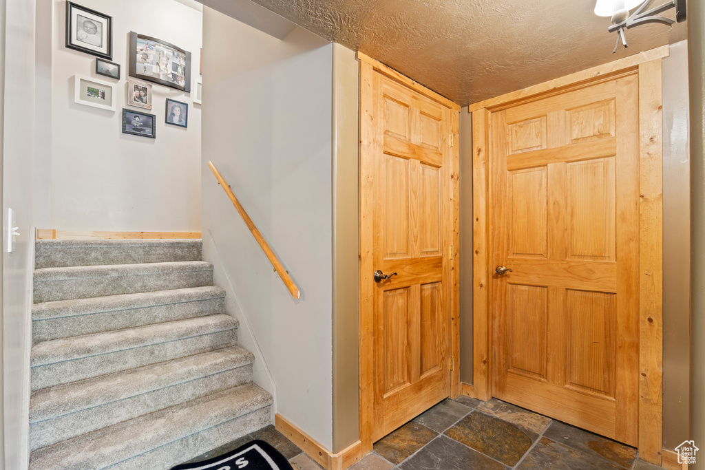 Stairs with stone finish floors and a textured ceiling