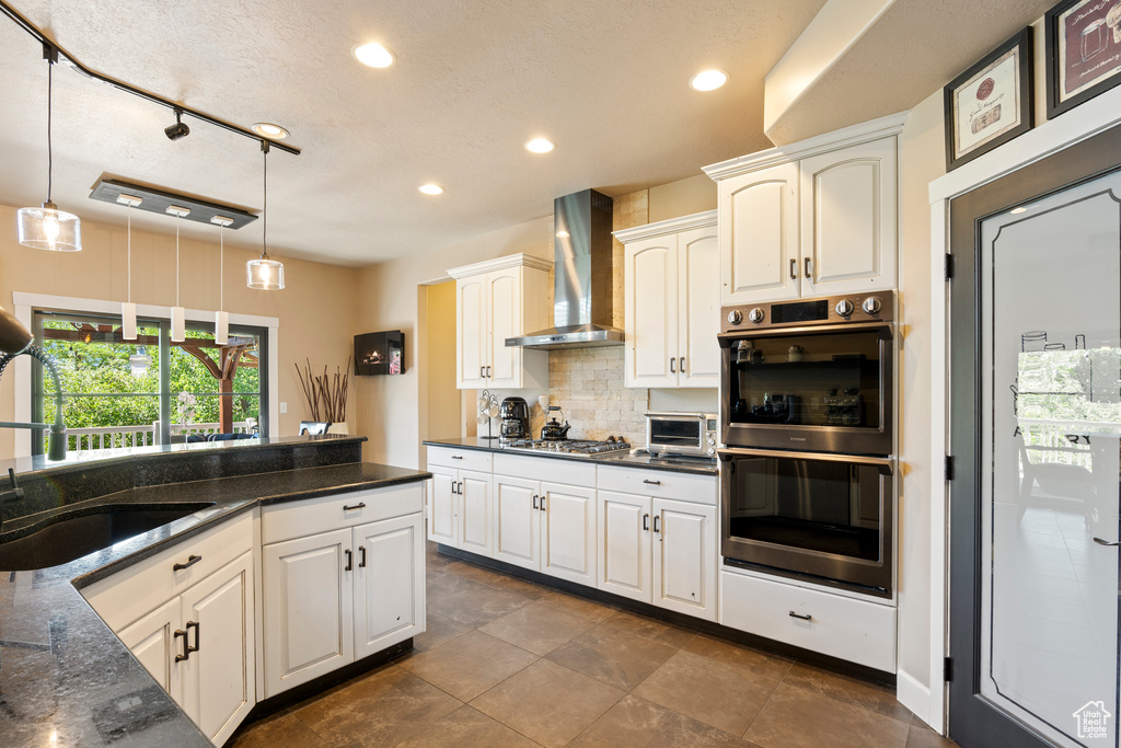 Kitchen with wall chimney exhaust hood, stainless steel appliances, recessed lighting, decorative light fixtures, and decorative backsplash