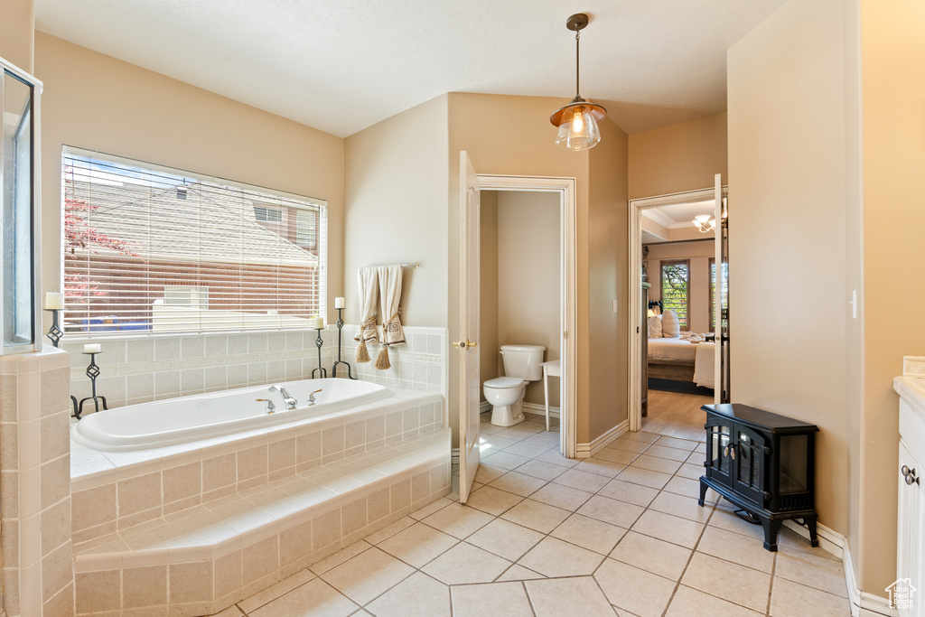 Bathroom featuring a bath, tile patterned floors, a wood stove, and ensuite bathroom