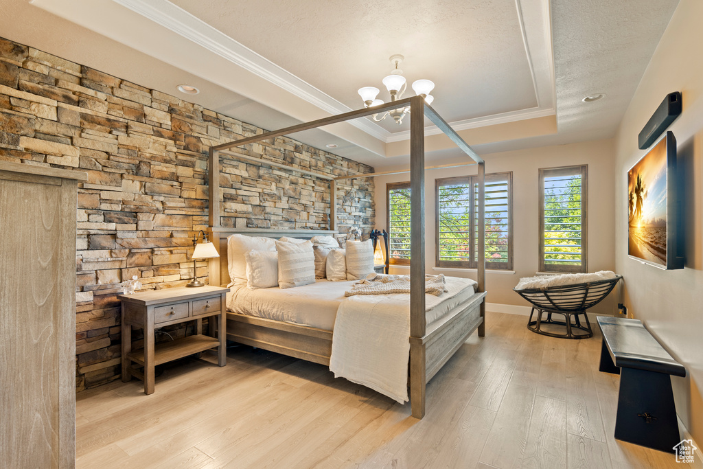 Bedroom featuring crown molding, a tray ceiling, wood finished floors, a chandelier, and recessed lighting