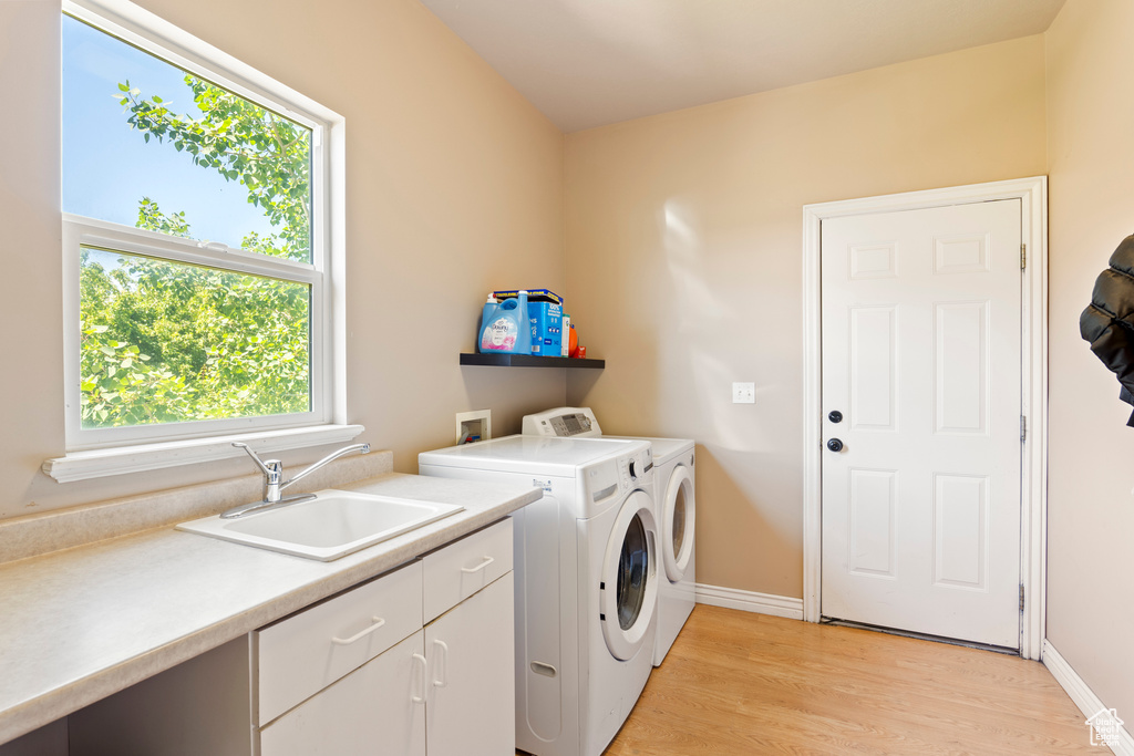 Laundry area featuring cabinet space, independent washer and dryer, healthy amount of natural light, and light wood finished floors