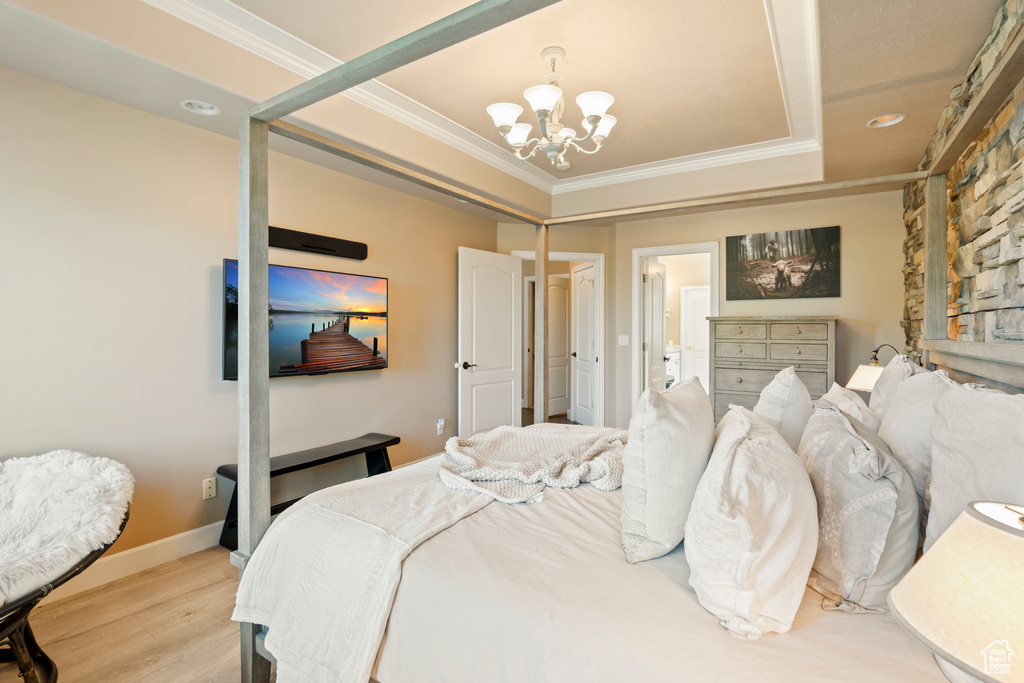 Bedroom with a chandelier, light wood-type flooring, ornamental molding, recessed lighting, and a tray ceiling
